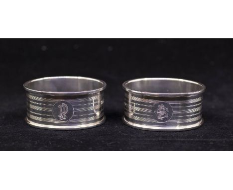A pair of George V silver engine turned shaped oval napkin rings, each engraved with an initial, hallmarked Chester, 1924, 1.