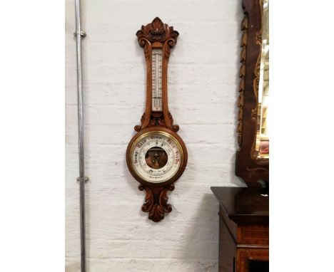 E Marston Loughborough an oak cased aneroid wall barometer with thermometer, carved scrolls to top and bottom, overall 87cm