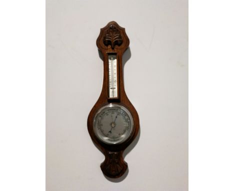 A small oak cased aneroid wall barometer with thermometer, carved detail to top and bottom, overall 60cm.