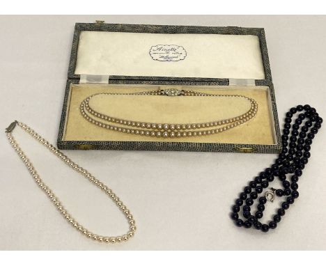 A boxed double row of vintage faux "Ainette" pearls. Together with a faux pearl necklace with stone set clasp and a blue glas