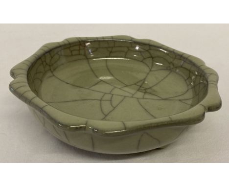 A Chinese green crackle glaze stoneware shallow bowl, raised on tripod feet.  Approx. 15.5cm diameter.