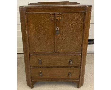 A vintage dark oak tallboy with 2 drawers and 2 door cupboard. Interior shelves to cupboard and decorative metal drop down ha