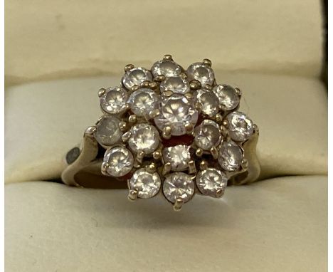 A 9ct gold and clear stone large cluster style dress ring. Set with 19 round cut clear stones. Hallmarks to inside of band. R