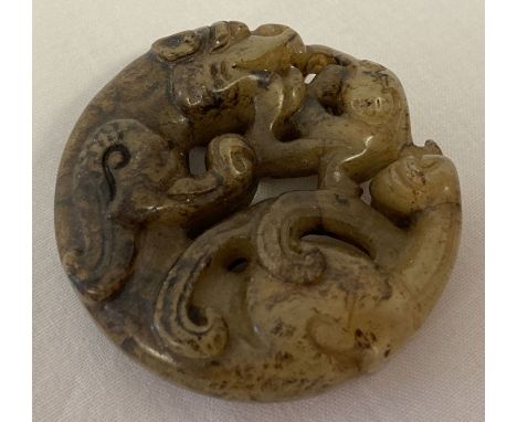 A Chinese Jade carved roundel depicting mythical creatures. Carved detail to both sides. Approx. 5cm diameter.