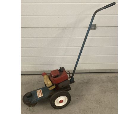 A vintage 1970's petrol push strimmer on wheels with a Tecumseh engine.  