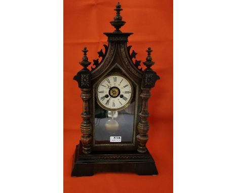 American Ansonia Mantel Clock in a walnut and gothic influenced case, with a visible bell and a 24-hour dial, 55cm x 30cm