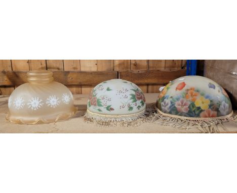 Three Art Deco style glass lampshades, two with a beaded trim, and one with a scalloped edge, all three with painted floral d