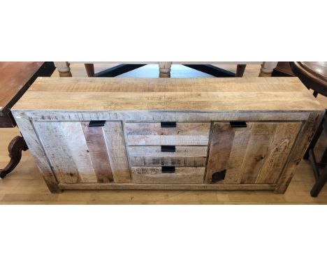 A modern mango wood sideboard, having three central drawers, flanked by two cupboard doors opening to fitted shelves within, 