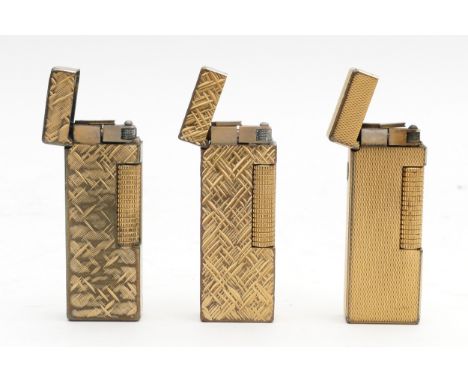 Alfred Dunhill Ltd; Three 1970s Dunhill rollagas pocket cigarette lighters, gold plated with engine turned decoration, one bo