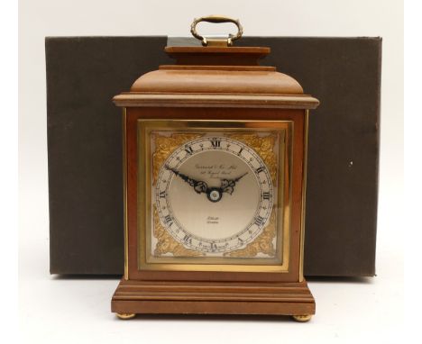 An Elliot mahogany cased mantel clock, with a silvered chapter dial featuring Roman Numerals, brass cherub spandrels to the c