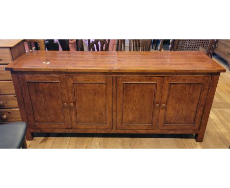 A modern Indonesian hardwood sideboard, having plank effect top over two pairs of cupboard doors, raised on square stile supp
