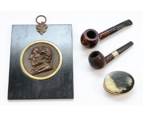 Four collectable items, to include, a bronze repousse portrait of a man, a horn snuff box, and two estate pipes, one with a s