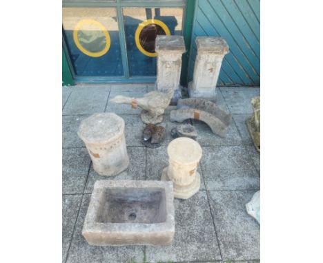 A collection of composition stone garden statuary, to include a pair of columns 65cm tall, animal models, a trough planter 49