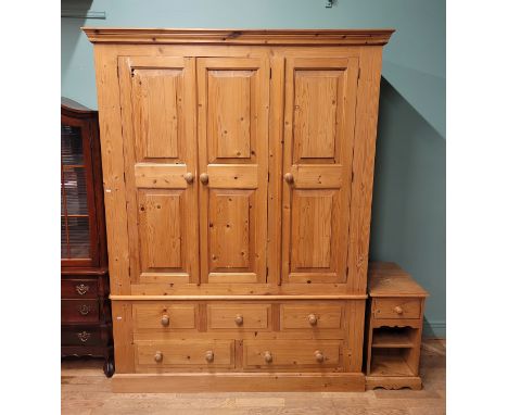 A substantial modern waxed pine triple wardrobe, having three panelled doors over three short and three long drawers, on a pl
