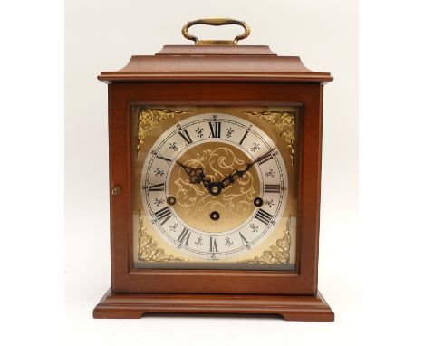 A Hermle mahogany-cased mantel clock with a silvered chapter ring featuring Roman Numerals and cherub spandrels, striking on 
