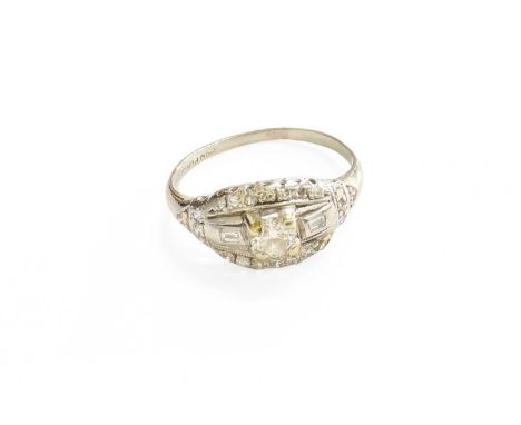 A Diamond Ring, the central round brilliant cut diamond in a white claw setting, flanked by baguette cut diamonds, to a borde