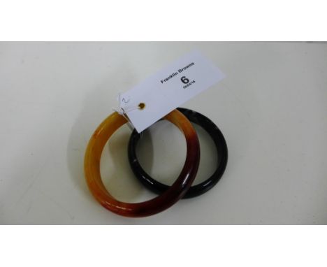 Two polished jade bangles to include spinach green jade and a russet example, smallest 7cm diameter (2) 