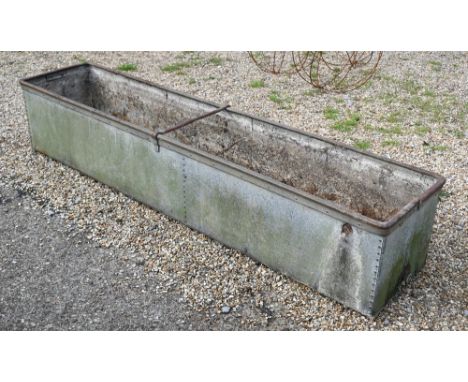 A large weathered riveted galvanised agricultural water trough, 214 cm x 47 cm x 40 cm h, note patch to one end, holed 