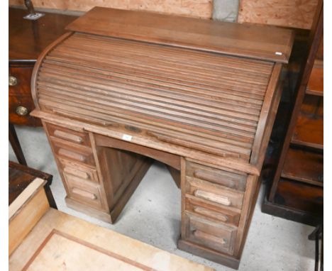 A compact light oak roll top desk, with nine drawers, raised on twin plinth bases to castors - by repute owned by David Sheph