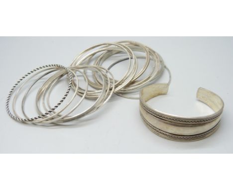 A white metal cuff bangle, four other white metal bangles, and thirteen stamped silver bangles, 130g total