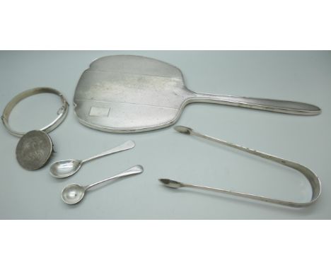 A silver backed mirror, a silver bangle, a silver salt spoon, a pair of silver sugar bows and a Georgian crown with pin mount
