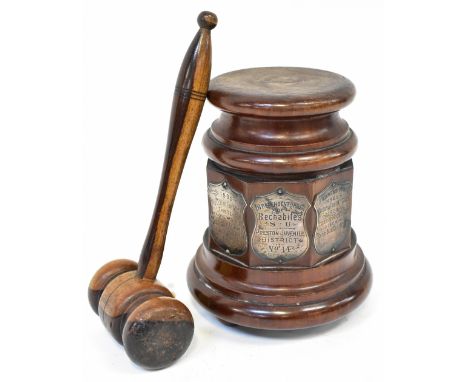 An early 20th century mahogany gavel block with turned and faceted design, raised on three ball feet, supporting three silver