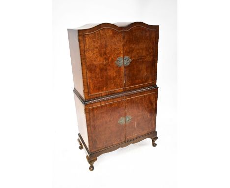 A mid-20th century crossbanded burr walnut veneered double dome topped cocktail cabinet, with ornate lock escutcheons, the up