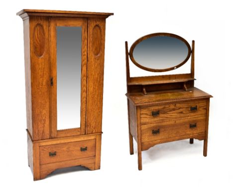 An early 20th century oak two-piece bedroom suite comprising a wardrobe with single mirrored door set with bevelled plate, fl