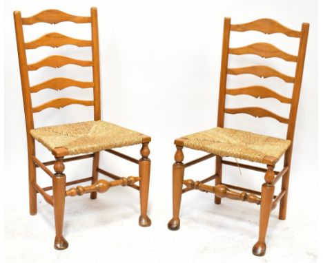 A set of six light oak reproduction Lancashire ladder back chairs, with rush seat united by bobbin turned stretchers, on fron
