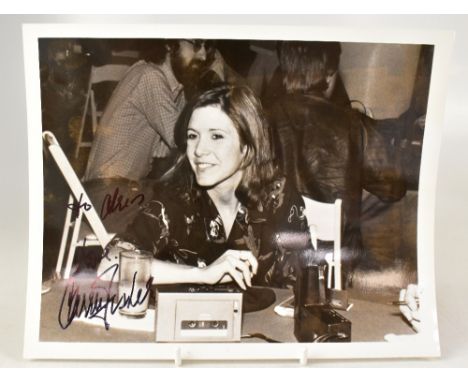 CARRIE FISHER; a reproduced black and white photograph of the actress, in a relaxed pose, bearing her signature, 20 x 25cm.We