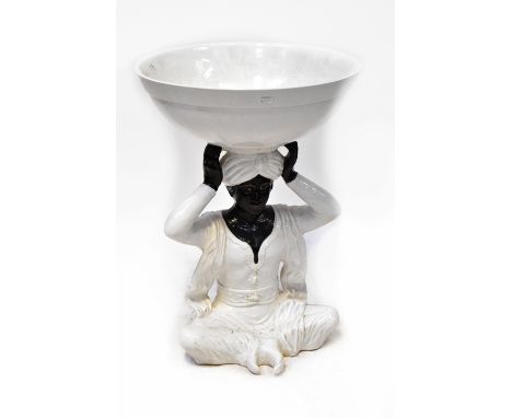 A 20th century ceramic decorative Blackamoor plant stand, with large circular white glazed bowl on the head of a seated gentl