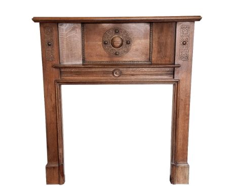 An early 20th century Arts &amp; Crafts style oak fire surround, with a carved Celtic-style shield to the centre panel, with 