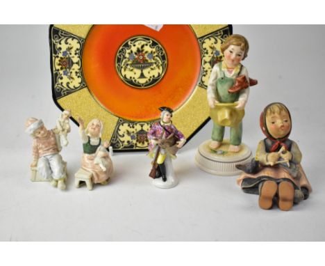 Two Hummel figures comprising a young girl with bird and a young boy carrying boots and holding a straw bonnet, three late 19