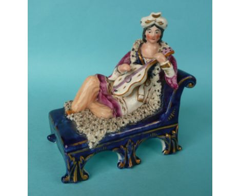 A good Staffordshire pottery group depicting a lady in Eastern costume reclining on a bed and playing the violin, circa 1840,