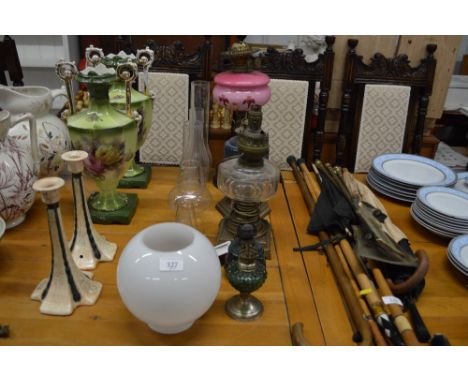 Four oil lamps, a converted oil lamp, glass chimneys and milk glass shade