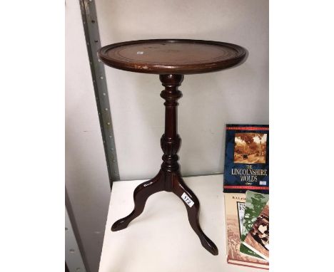 A dark wood stained tripod wine table with leather insert in top