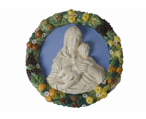 An early 20th Century Della Robbia type majolica roundel, the centre with the virgin and child in white relief reserved again