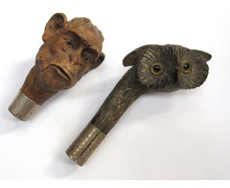 A Victorian Black Forest carved owls head walking stick handle with glass eyes and worn silver mount and a monkey head handle