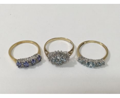 Three gold rings set with aquamarine, blue and clear stones, approx 7.8g and size R.