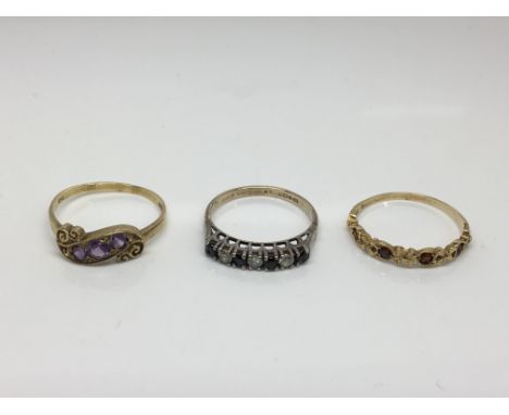 Three gold rings, one inset with amethyst, one with garnets and one with sapphires (3).