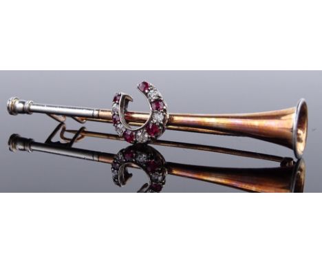 An unmarked gold ruby and diamond set hunting design brooch, with hunting horn body and gem set horseshoe motif, length 64.9m