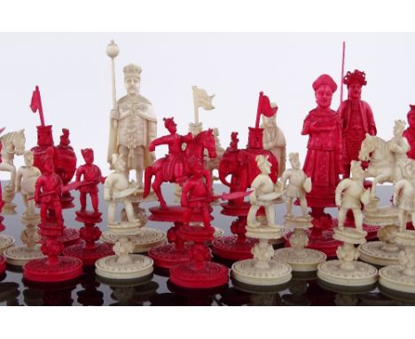 A Chinese 19th century finely carved red and white stained ivory chess set in the form of emperors and warriors, king height 