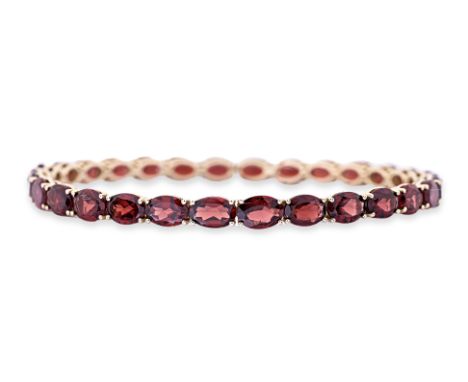 A GARNET FULL ETERNITY BANGLE Featuring oval cut garnets totalling approximately 30.0 Cts, mounted in an 18K yellow gold sett