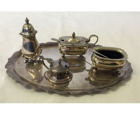 A silver plated condiment set on oval tray with spoons & blue glass liners.