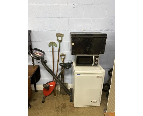A black coloured tin trunk, 60cm L, various garden tools, exercise bike, microwave and an Ice Tech freezer
