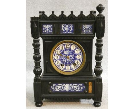 A late 19th century ebonised Gothic style bracket clock with blue and white ceramic dial and inlaid panels standing on turned