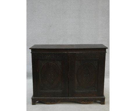 An antique country oak hall cupboard with a pair of carved panel doors on bracket feet. H.64 W.82 D.28cm 
