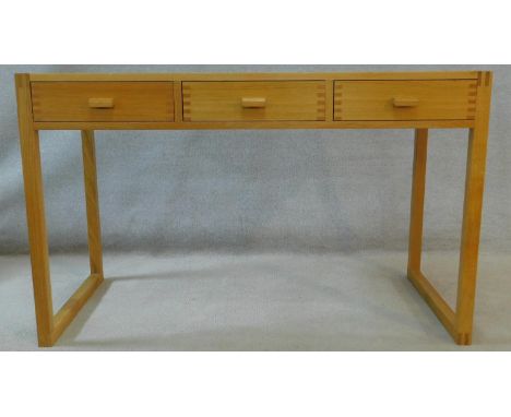 A contemporary light oak writing table fitted with three frieze drawers on trestle style base. H.75 W.121 D.60cm 