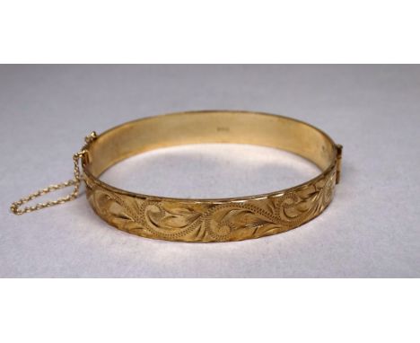 A 9ct yellow gold bangle - with foliate engraving, weight 19.5g. 