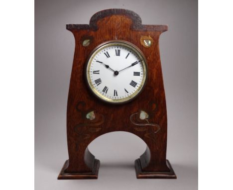 An early 20th century Arts and Crafts style oak mantel clock - in the manner of Liberty, the white enamel dial set out in Rom